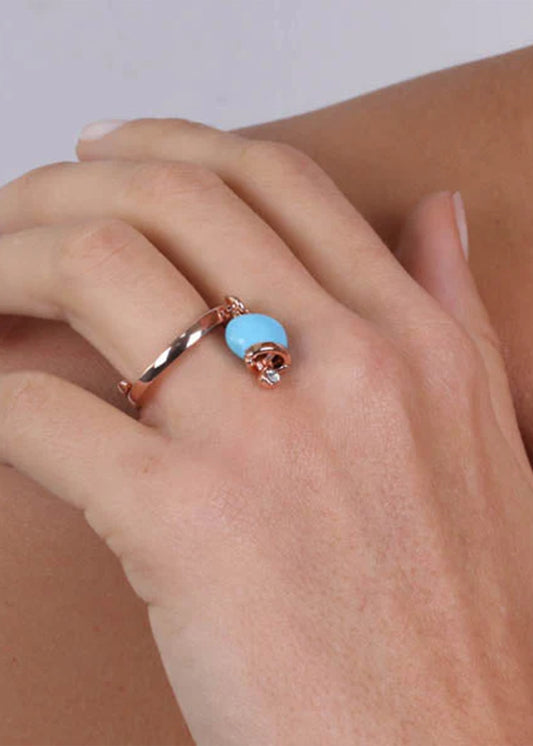 Gold-colored metal ring with a blue pendant lucky bell and a light point